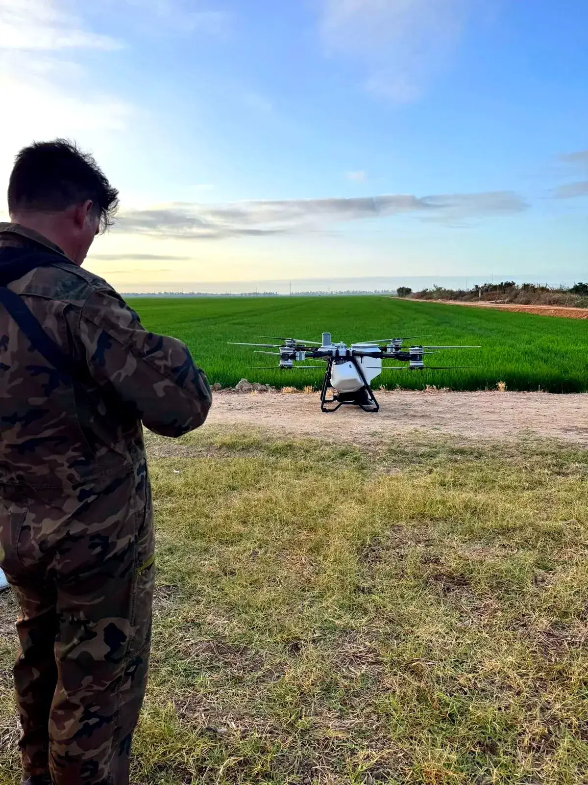 Dron agrícola pulverizando junto a una hilera de árboles