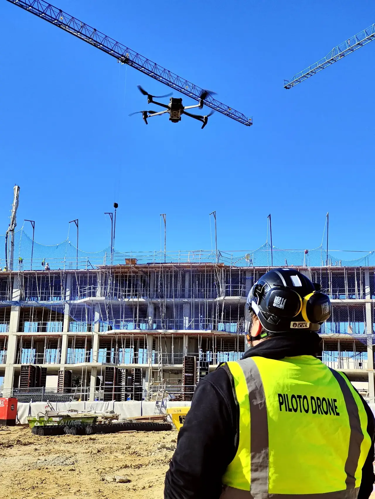 Piloto de dron con equipo de protección en una obra de construcción